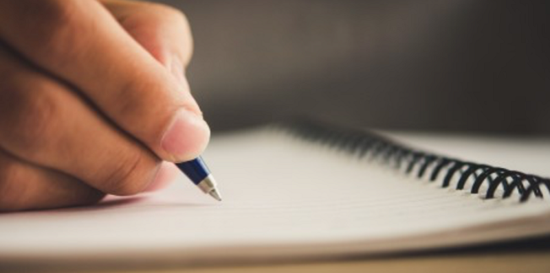 دستی در حال نوشتن با خودکار