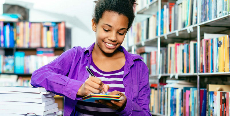 نوجوان سیاه‌پوستی در کتابخانه پر از کتاب