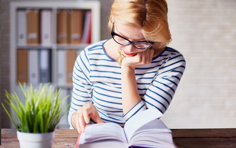 دختری که دست بر زیر چانه گذاشته و کتاب می‌خواند