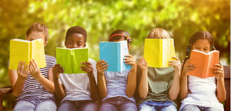 چند کودک کنار یکدیگر نشسته‌اند و کتاب می‌خوانند