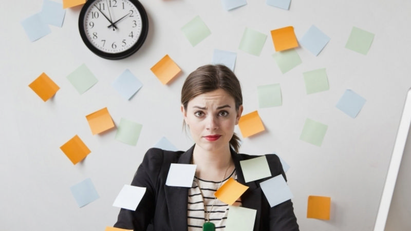 دختری که به دلیل وظایف زیاد کاغذهای چسبی اطرافش چسبیده و دچار استرس شده است