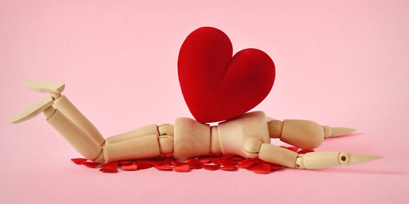 عروسکی چوبی که قلبی قرمز بر رویش افتاده است