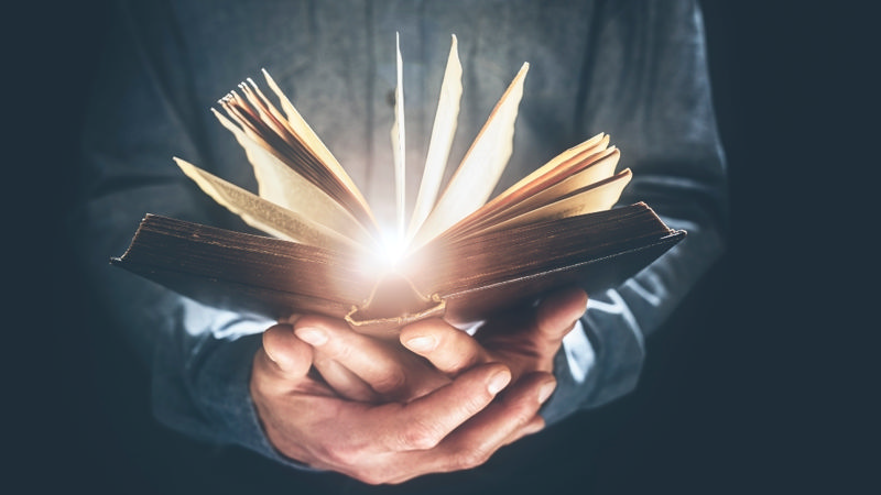 دستی که کتابی را گرفته است و از کتاب نور میبارد