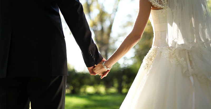 عروس و دامادی که دست همدیگر را گرفته‌اند