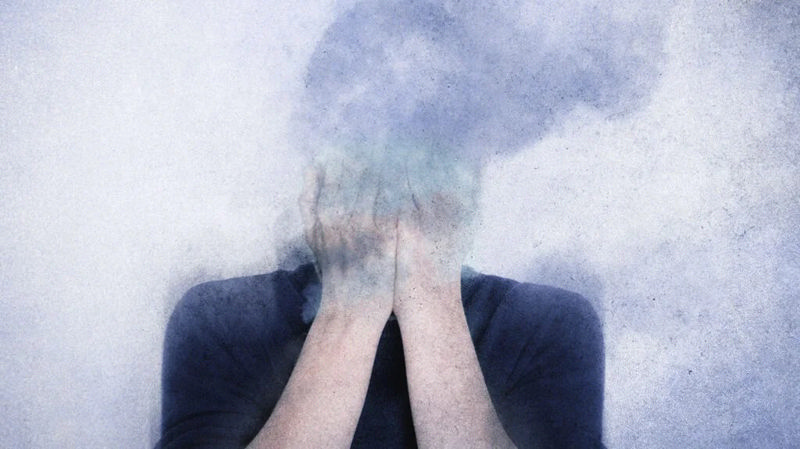 زنی که صورتش در میان دود محو شده و دستهایش را جلوی صورتش گرفته است