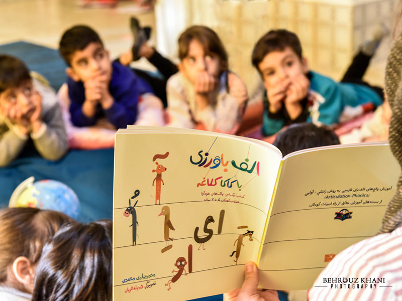 معلمی در حال یاد دادن ادبیات فارسی به کودکان